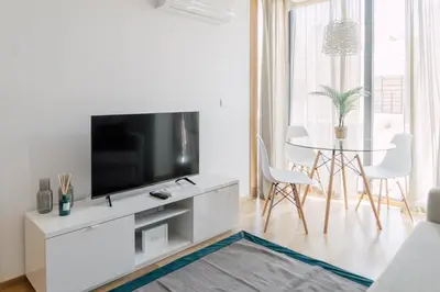 a white living room with a tv and a table at Oporto Yellow Apartments in Porto