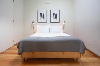 a bed in a room with two pictures on the wall at Batalha Garden Apartment in Porto