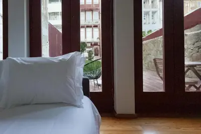 a bed with a pillow in front of a window at Batalha Garden Apartment in Porto