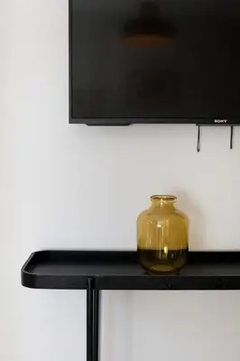 a glass jar sitting on a black shelf under a tv at VIVA Whilom Secret with garage in Porto