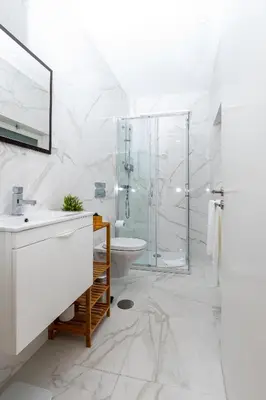 a white bathroom with a glass shower and a sink at Mouzinho 129 - Medronheiro & Oliveira in Porto