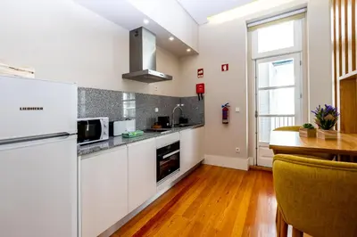 a kitchen with white cabinets and a wooden floor at Mouzinho 129 - Medronheiro & Oliveira in Porto