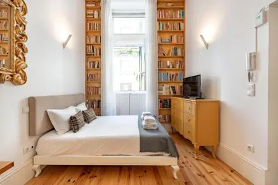 a bedroom with a bed and a television and bookshelves at VIVA Library Studio in Porto