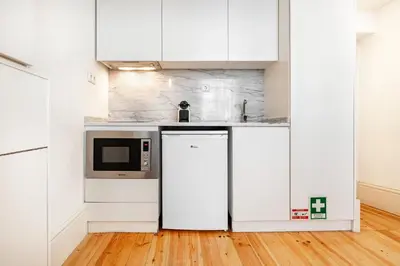 a kitchen with white cabinets and a microwave at VIVA Library Studio in Porto