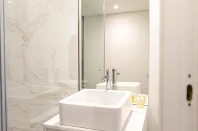 a white bathroom with a sink and a shower at N&N Home in Porto