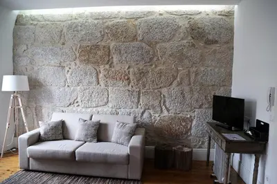 a living room with a couch and a stone wall at Citybreak-apartments Bolhao in Porto