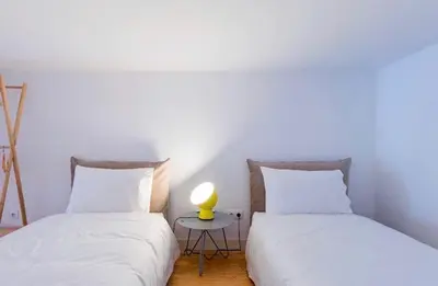 two beds with white sheets and a yellow lamp on a table at Porto Legend Apartments in Porto