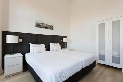 a bedroom with a large white bed with a black headboard at Porto Legend Apartments in Porto