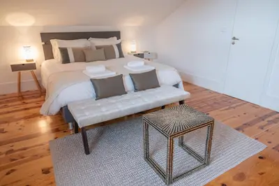 a bedroom with a large white bed with a bench at Tomas Loft in Porto