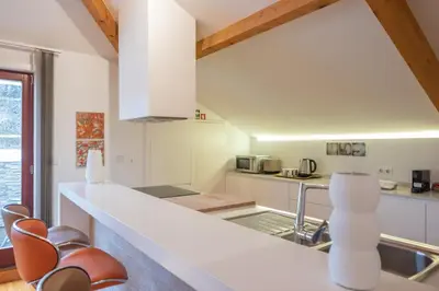 a kitchen with white cabinets and a counter with chairs at Tomas Loft in Porto