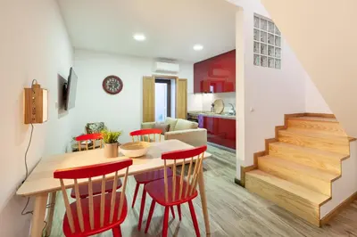 a kitchen and living room with a wooden table and red chairs at D&S - Alegria 630 in Porto