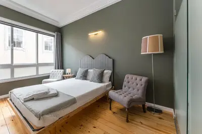 a bedroom with a bed and a chair and a lamp at GuestReady - Gold Leaf in Porto