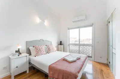 a white bedroom with a large bed and a window at GuestReady - Gold Leaf in Porto