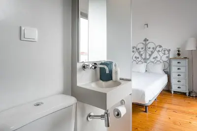 a white bathroom with a sink and a bed at GuestReady - Gold Leaf in Porto