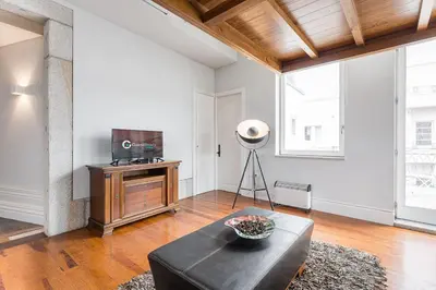 a living room with a black leather couch and a mirror at GuestReady - Charming Tree in Porto