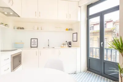 a kitchen with white cabinets and a large window at 12 Sweet Caroline in Porto