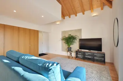 a living room with a blue couch and a flat screen tv at Sé do Porto - Loft with City View in Porto