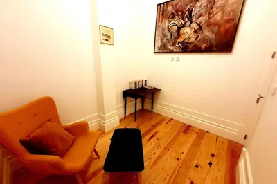 a living room with an orange chair and a table at OHH - General da Silveira Flat Deluxe Apartment - Downtown in Porto
