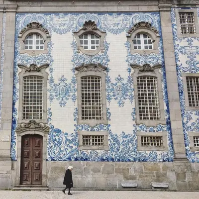 a man walking past a building with blue and white tiles at OHH - General da Silveira Flat Deluxe Apartment - Downtown in Porto