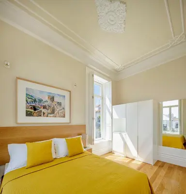 a bedroom with a yellow bed and two windows at Casa Kala in Porto