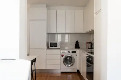 a white kitchen with a washing machine and a microwave at Belleville in Porto