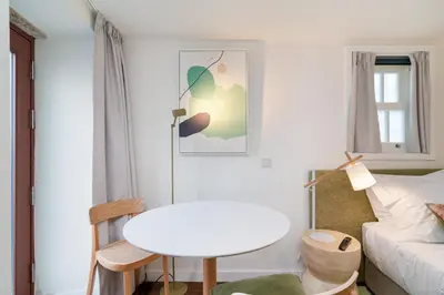 a living room with a white table and a bed at CHARM APARTMENTS PORTO - Centro Batalha 2 in Porto