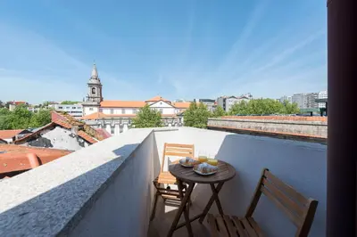 a balcony with two chairs and a table on a roof at Central Superb Flat w/ AC & Balcony by LovelyStay in Porto