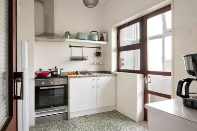 a small kitchen with white cabinets and a window at ! Luminous 2BR Top Floor ! Praça da República in Porto