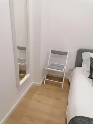 a bedroom with a bed and a mirror and a chair at TMJ Apartamento in Porto