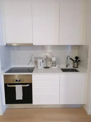a kitchen with white cabinets and a sink and a stove at TMJ Apartamento in Porto