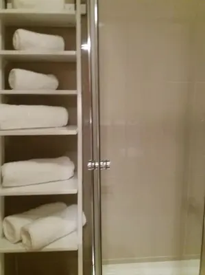 a bathroom with a towel rack with towels and a shower at KrisApartments 2 in Porto