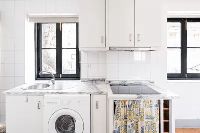 a white kitchen with a sink and a washing machine at GuestReady - Modern Comfort in Downtown in Porto