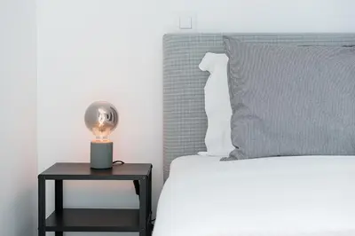 a bed with a lamp on a table next to a bed at GuestReady - Poet's Modern Retreat in Porto