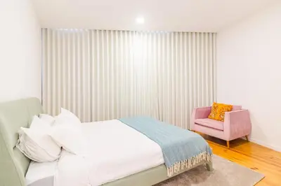 a bedroom with a bed and a pink chair at OHH- Padre António Vieira flat D - 2bedroom near the train station in Porto