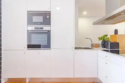 a kitchen with white cabinets and a stove at OHH- Padre António Vieira flat D - 2bedroom near the train station in Porto