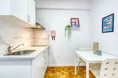 a kitchen with white cabinets and a sink and a table at Travel & Live Bragas in Porto