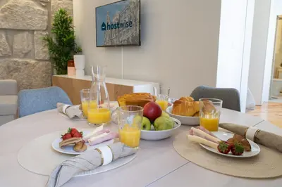 a table with plates of food and glasses of orange juice at Host Wise - Enchanting Design Flat - Premium Location in Porto