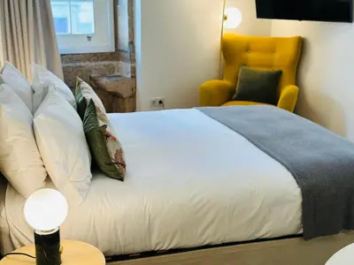 a bedroom with a bed and a yellow chair at CHARM APARTMENTS PORTO - Centro Batalha 1 in Porto