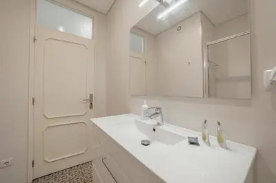 a white bathroom with a sink and a mirror at Downtown Design Apartment With Balcony by Vacationy in Porto