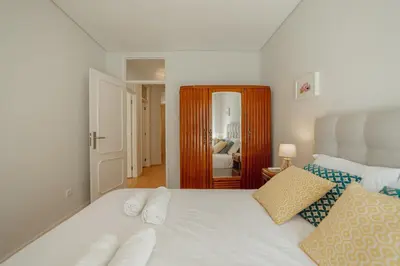 a bedroom with a white bed with pillows and a mirror at Downtown Design Apartment With Balcony by Vacationy in Porto