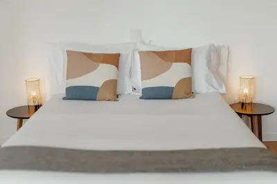 a large white bed with pillows and two tables at Courtyard Oporto Design Apartments by Vacationy in Porto