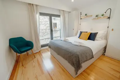 a bedroom with a bed and a blue chair at Courtyard Oporto Design Apartments by Vacationy in Porto