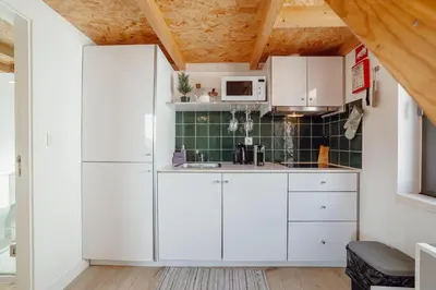 a kitchen with white cabinets and a green tile wall at Mezzanine Stylish Apartments by Vacationy in Porto
