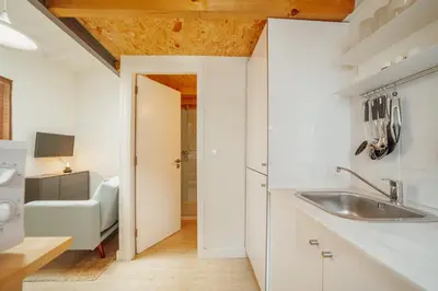 a white kitchen with a sink and a chair at Mezzanine Stylish Apartments by Vacationy in Porto