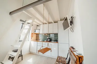 a loft kitchen with white cabinets and a ladder at Mezzanine Stylish Apartments by Vacationy in Porto