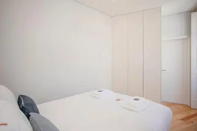 a white bedroom with a bed and a closet at Liiiving in Porto - Aliados Stone Apartment in Porto