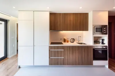 a kitchen with white walls and wooden cabinets at Paraíso Apartment in Porto