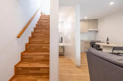 a living room and kitchen with a staircase in a house at Downtown A whole house duplex designed for remote work and near metro lapa in Porto