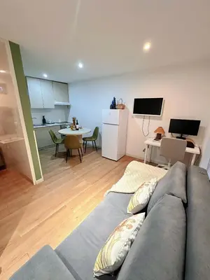 a living room with a gray couch and a kitchen at Downtown A whole house duplex designed for remote work and near metro lapa in Porto