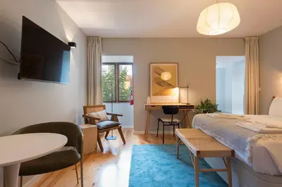 a kitchen with white cabinets and a table and chairs at Porto Central Loft II in Porto